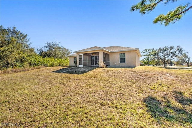 rear view of house featuring a sunroom and a yard