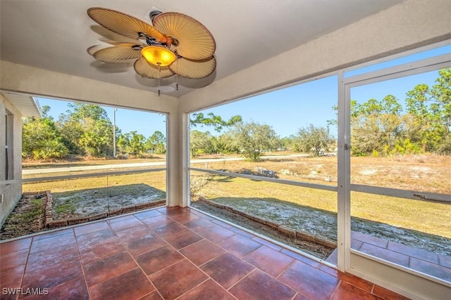 unfurnished sunroom featuring ceiling fan and a healthy amount of sunlight