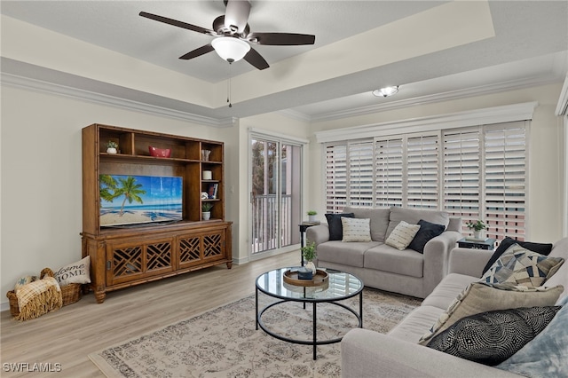 living room featuring ceiling fan, light wood-type flooring, and a tray ceiling