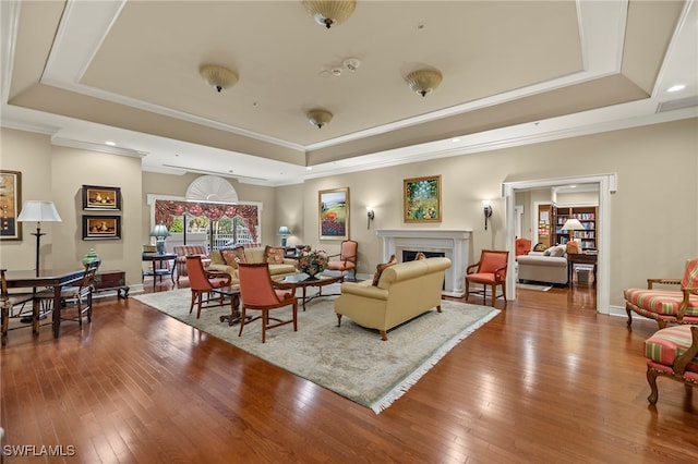 living room featuring hardwood / wood-style flooring, a tray ceiling, and crown molding