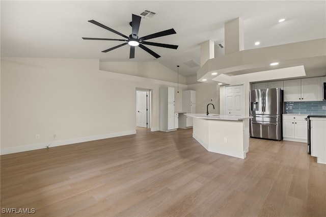 kitchen with pendant lighting, stainless steel refrigerator with ice dispenser, decorative backsplash, a kitchen island with sink, and ceiling fan