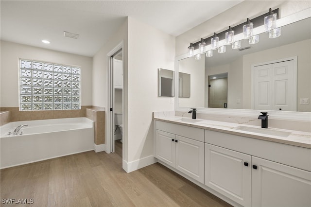 full bathroom featuring hardwood / wood-style floors, toilet, vanity, and separate shower and tub