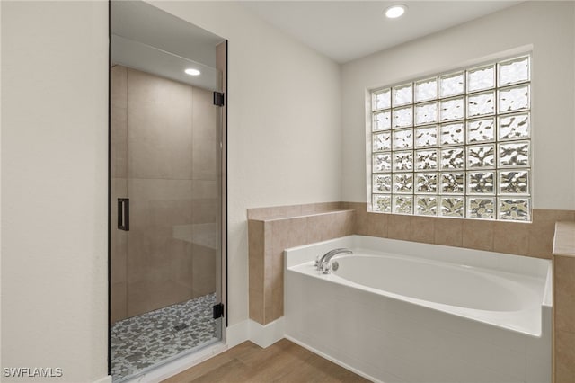 bathroom featuring wood-type flooring and shower with separate bathtub