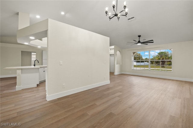 unfurnished living room with light hardwood / wood-style floors, sink, lofted ceiling, and ceiling fan with notable chandelier