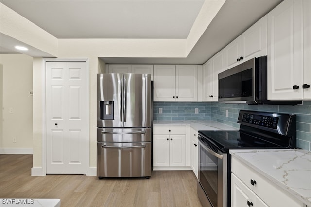 kitchen featuring white cabinetry, appliances with stainless steel finishes, backsplash, light wood-type flooring, and light stone countertops