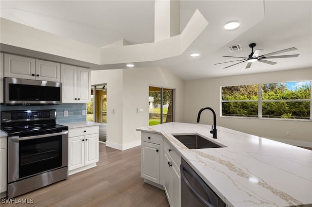 kitchen with ceiling fan, stainless steel appliances, backsplash, light stone counters, and sink