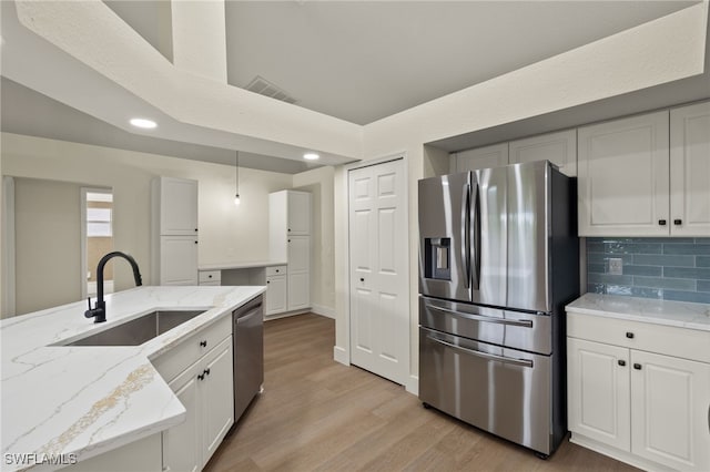 kitchen featuring white cabinetry, appliances with stainless steel finishes, tasteful backsplash, pendant lighting, and sink