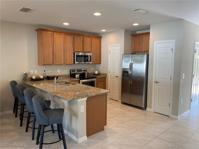 kitchen featuring light stone countertops, stainless steel appliances, kitchen peninsula, and sink