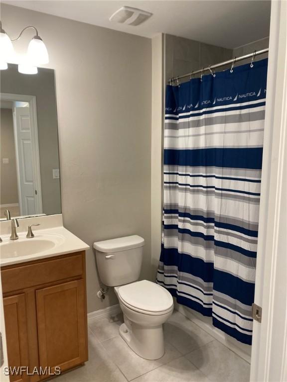 bathroom featuring tile patterned flooring, a shower with curtain, vanity, and toilet