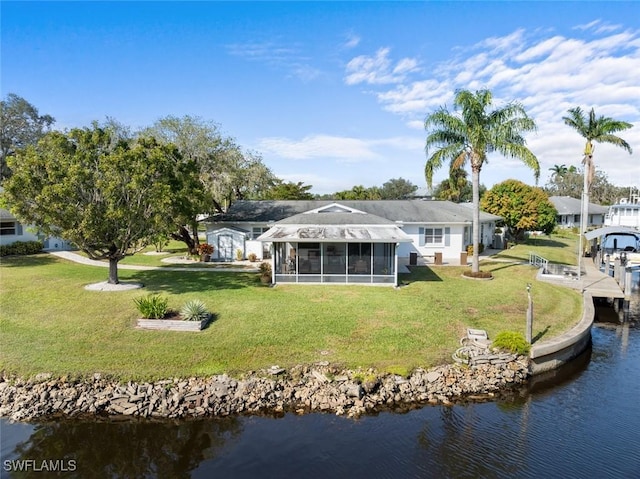 rear view of house with a sunroom, a water view, and a yard