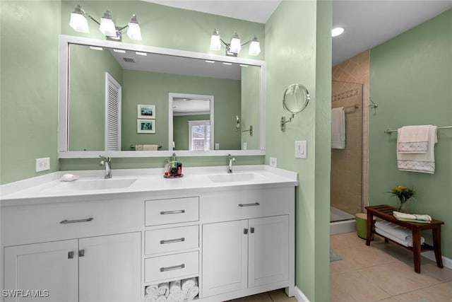 bathroom with tile patterned flooring, vanity, and a tile shower