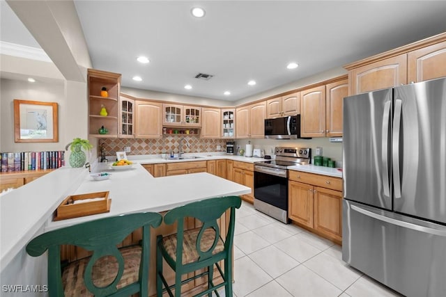 kitchen with sink, stainless steel appliances, a kitchen breakfast bar, kitchen peninsula, and light tile patterned flooring