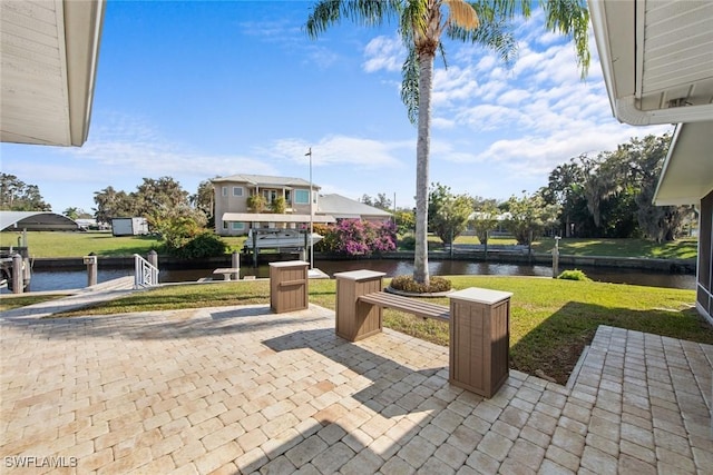 surrounding community with a lawn, a patio area, and a water view