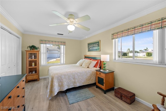 bedroom featuring ceiling fan, light hardwood / wood-style floors, multiple windows, a closet, and ornamental molding