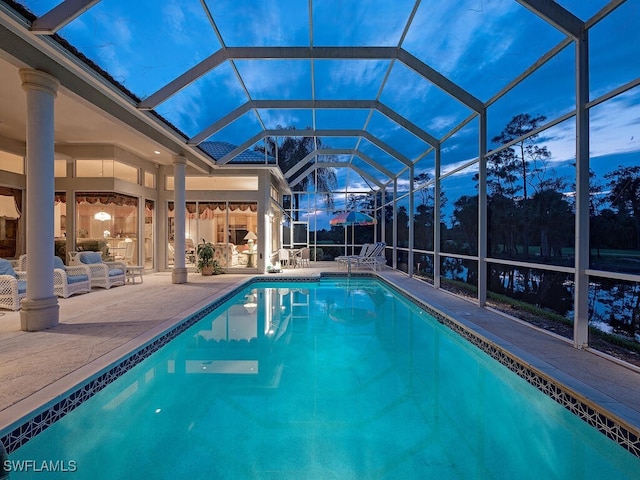 pool at dusk with a patio, an outdoor hangout area, and a lanai