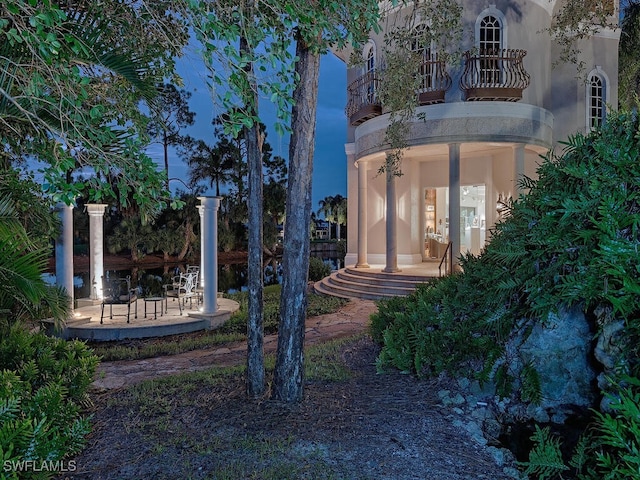 yard at dusk featuring a balcony