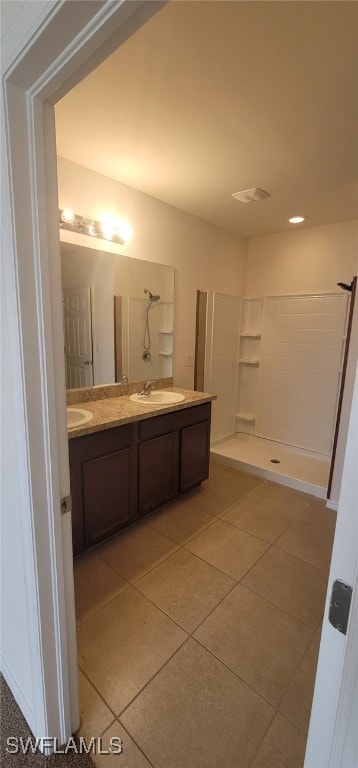 bathroom with tile patterned flooring, a shower, and vanity