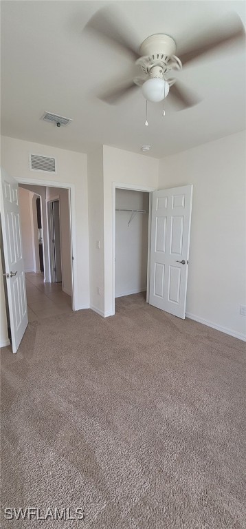 unfurnished bedroom featuring ceiling fan, light colored carpet, and a closet