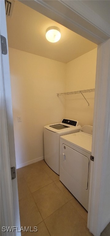 clothes washing area with washing machine and clothes dryer and tile patterned floors