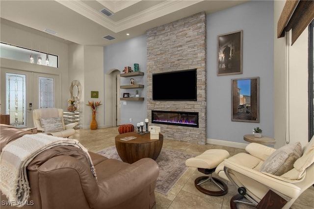 living room featuring french doors, a raised ceiling, a fireplace, and crown molding