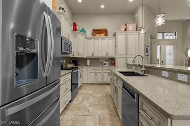 kitchen with sink, light stone counters, backsplash, hanging light fixtures, and appliances with stainless steel finishes