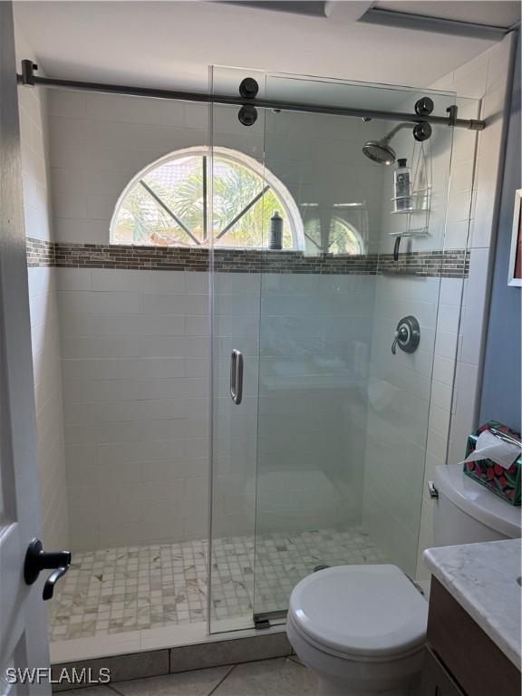 bathroom with toilet, tile patterned flooring, a shower with shower door, and vanity