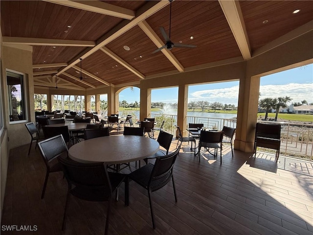 dining area featuring wood ceiling, ceiling fan, dark wood finished floors, lofted ceiling with beams, and a water view
