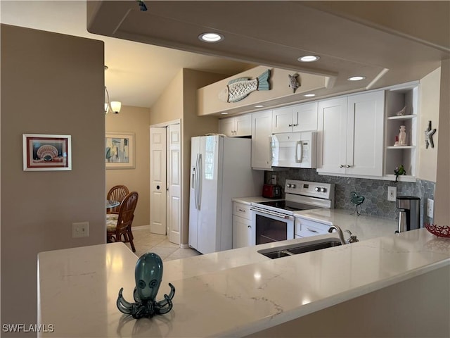 kitchen featuring sink, light stone counters, white appliances, kitchen peninsula, and decorative backsplash