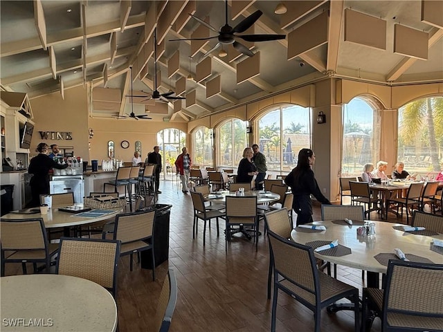 dining area featuring dark wood-type flooring, high vaulted ceiling, and ceiling fan