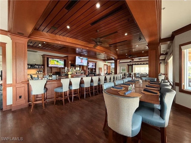 dining area with a healthy amount of sunlight, a ceiling fan, ornate columns, and dark wood-style floors