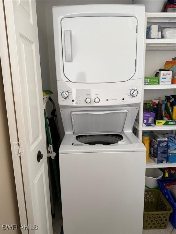 clothes washing area with tile patterned flooring and stacked washer / dryer