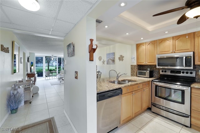 kitchen featuring light stone counters, sink, appliances with stainless steel finishes, and light tile patterned flooring