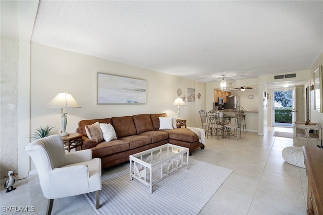 living room with ceiling fan, a textured ceiling, and light tile patterned floors