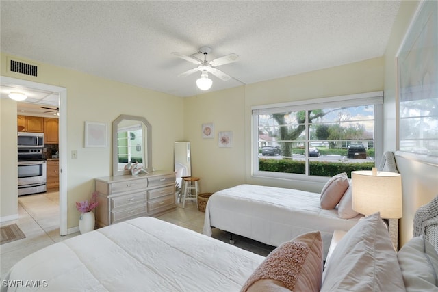 bedroom with ceiling fan, light tile patterned flooring, and a textured ceiling