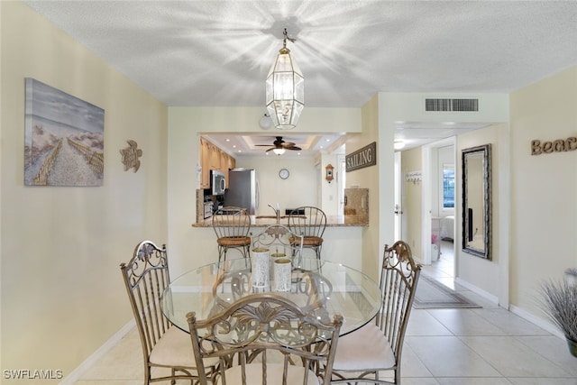 tiled dining space with a textured ceiling and ceiling fan with notable chandelier