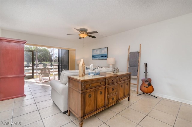 living room featuring ceiling fan, light tile patterned floors, and a textured ceiling