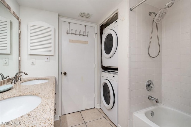 bathroom featuring tile patterned floors, vanity, stacked washer / dryer, and tiled shower / bath