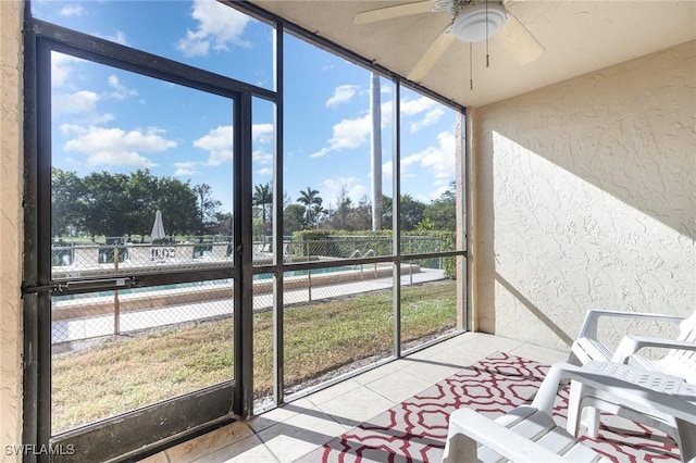 sunroom with ceiling fan and a water view