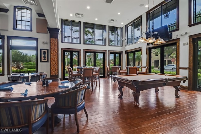 rec room with pool table, hardwood / wood-style flooring, a towering ceiling, and french doors