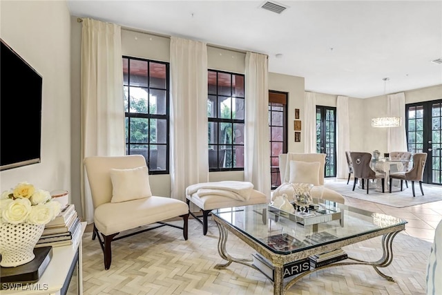 sitting room with light parquet floors and a notable chandelier