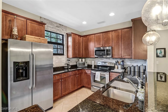 kitchen with sink, stainless steel appliances, dark stone countertops, and hanging light fixtures