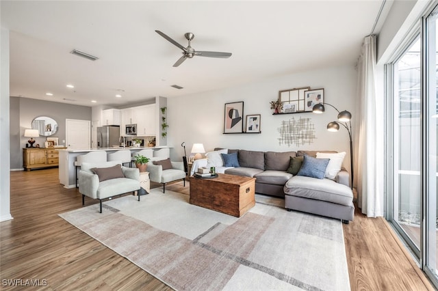 living room with ceiling fan and light hardwood / wood-style floors