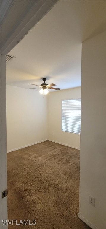 spare room with ceiling fan and dark colored carpet