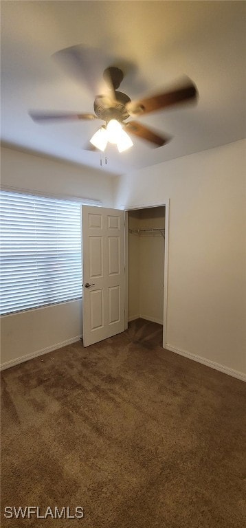 unfurnished bedroom with a closet, dark carpet, and ceiling fan