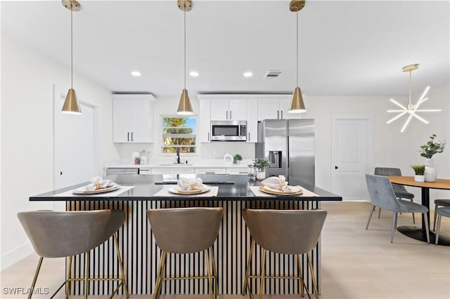 kitchen with a kitchen breakfast bar, a kitchen island, white cabinets, and appliances with stainless steel finishes