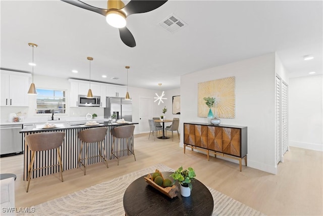 living room with light wood-type flooring, ceiling fan, and sink