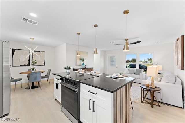 kitchen featuring appliances with stainless steel finishes, decorative light fixtures, white cabinets, a center island, and a breakfast bar area