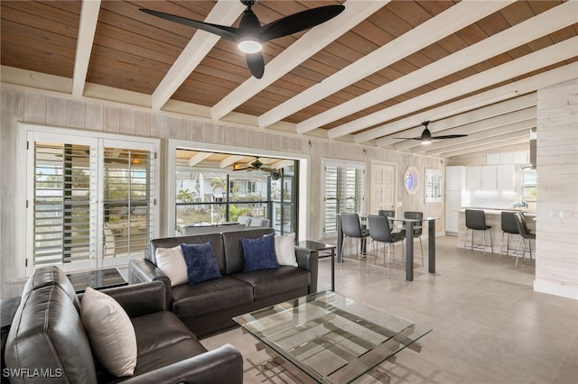 living room with vaulted ceiling with beams, wood ceiling, ceiling fan, and wood walls