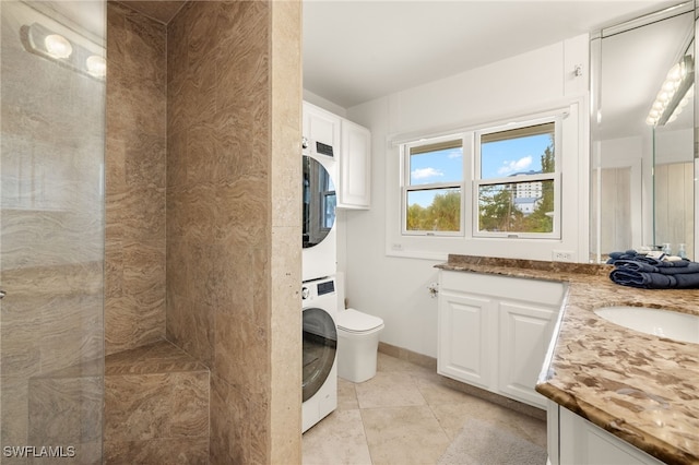 bathroom with stacked washer / dryer, vanity, tile patterned floors, and toilet