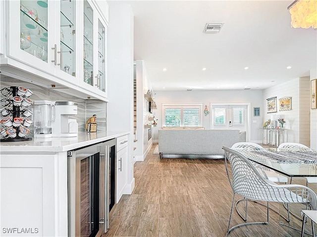 kitchen featuring white cabinets, beverage cooler, and light hardwood / wood-style flooring